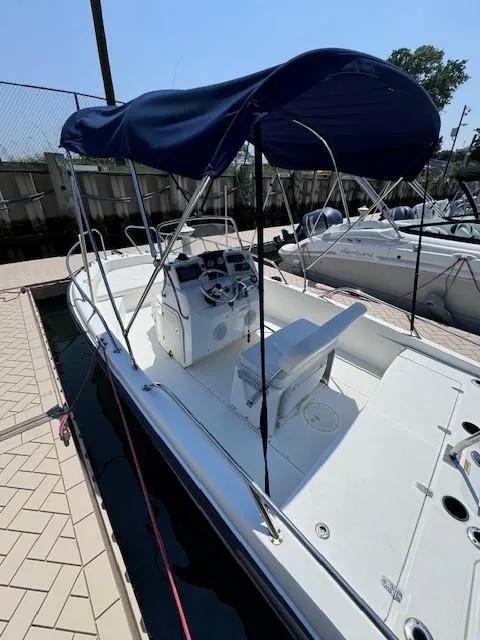 Slide: The Image of 2012 Boston Whaler 180 Dauntless boat with blue canopy docked at marina. - 8