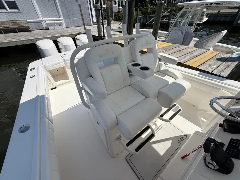 Slide: The Image of 2017 Regulator 34SS boat with white seating and dual cup holders at dock. - 34