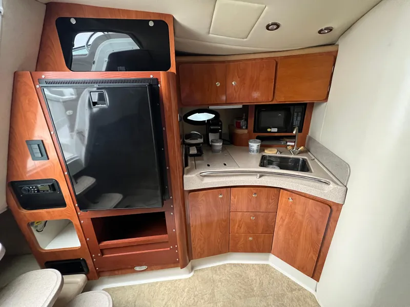 Slide: The Image of 2004 Wellcraft 3700 Martinique yacht kitchen with wood cabinets, sink, and appliances. - 18