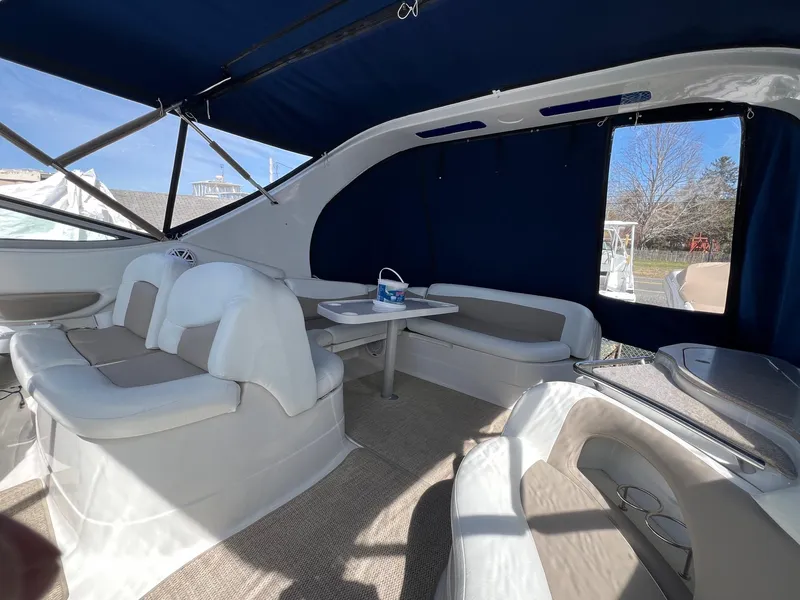 Slide: The Image of 2004 Wellcraft 3700 Martinique boat interior with white seating and table under blue canopy. - 9
