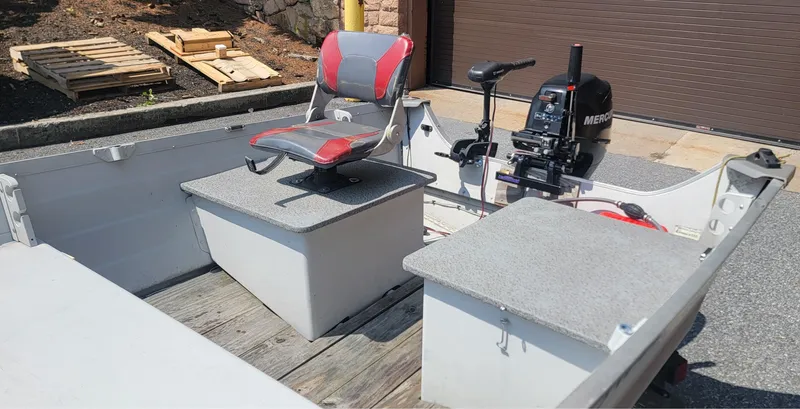 Slide: The Image of 2010 Starcraft SF 1415 boat interior with motor and seating, parked outdoors. - 3