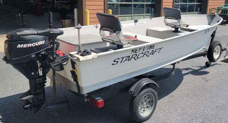 Slide: The Image of 2010 Starcraft SF 1415 boat with Mercury motor on trailer, parked outdoors. - 6