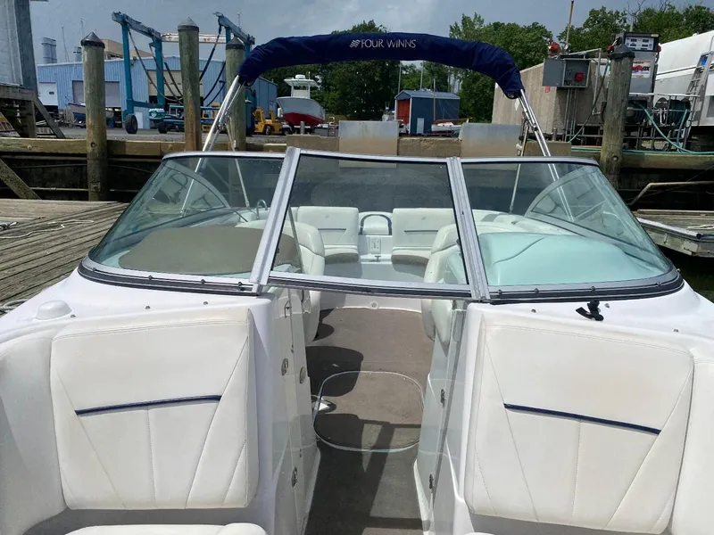 Slide: The Image of 2007 Four Winns 240 Horizon boat docked, featuring white seating and a blue canopy. - 4