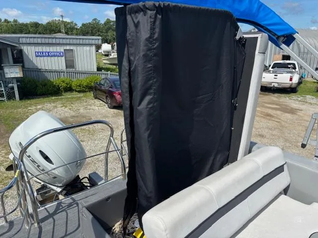 Slide: The Image of 2022 Sweetwater 2286 boat with black privacy curtain and outboard motor, parked near sales office. - 17