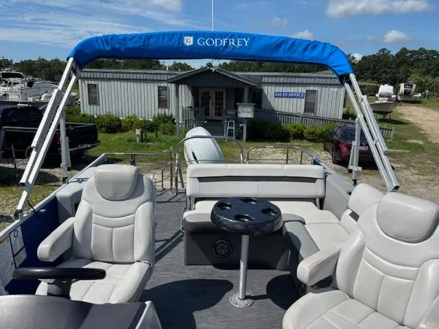 Slide: The Image of 2022 Sweetwater 2286 pontoon boat with blue canopy, parked near sales office. - 20