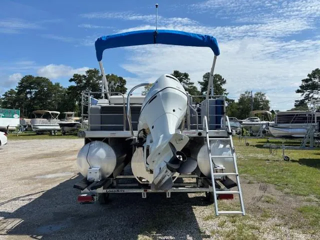 Slide: The Image of 2022 Sweetwater 2286 pontoon boat with outboard motor, parked outdoors under blue sky. - 6