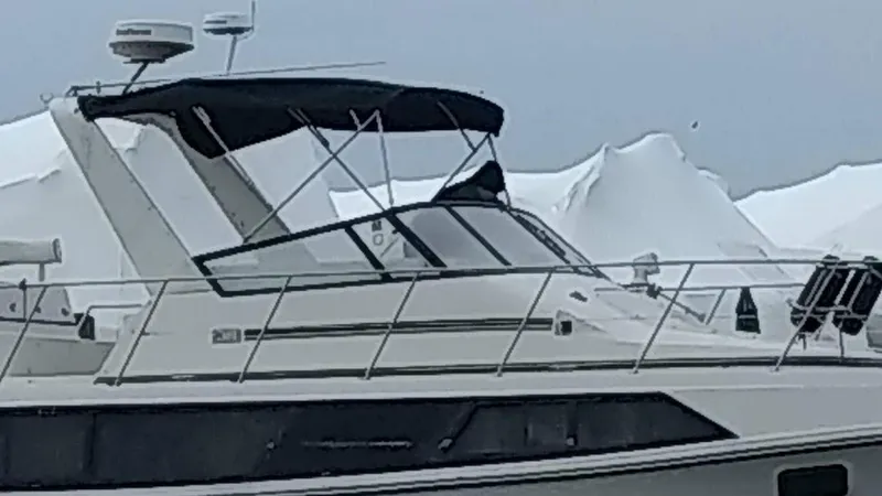 The Image of 1986 Carver 36 Mariner yacht with black canopy, docked against a snowy backdrop. - 0