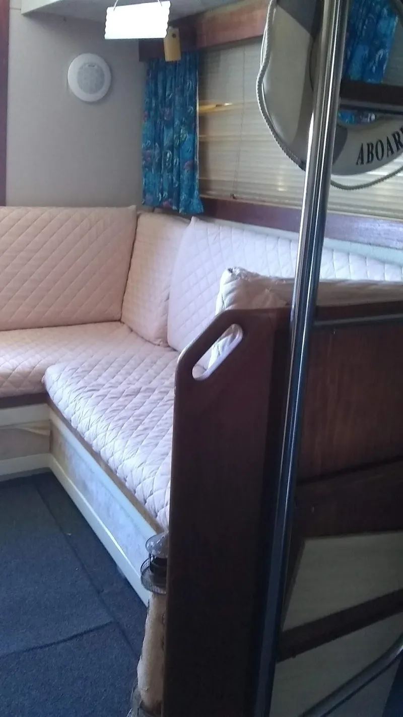 Slide: The Image of Interior of 1986 Carver 36 Mariner with cushioned seating and blue curtains. - 5