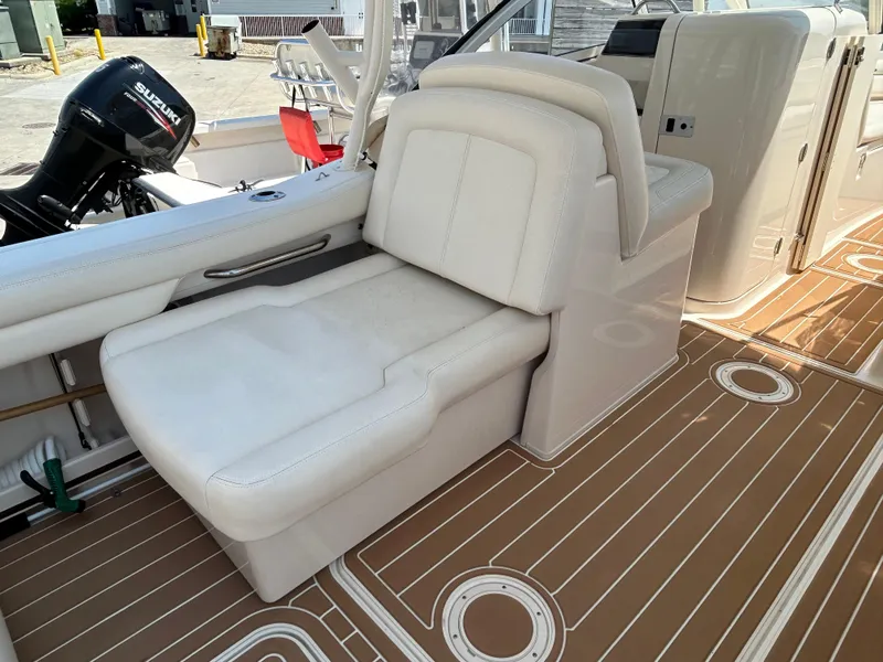 Slide: The Image of 2018 Grady-White Freedom 235 boat interior with white seating and Suzuki outboard motor. - 13