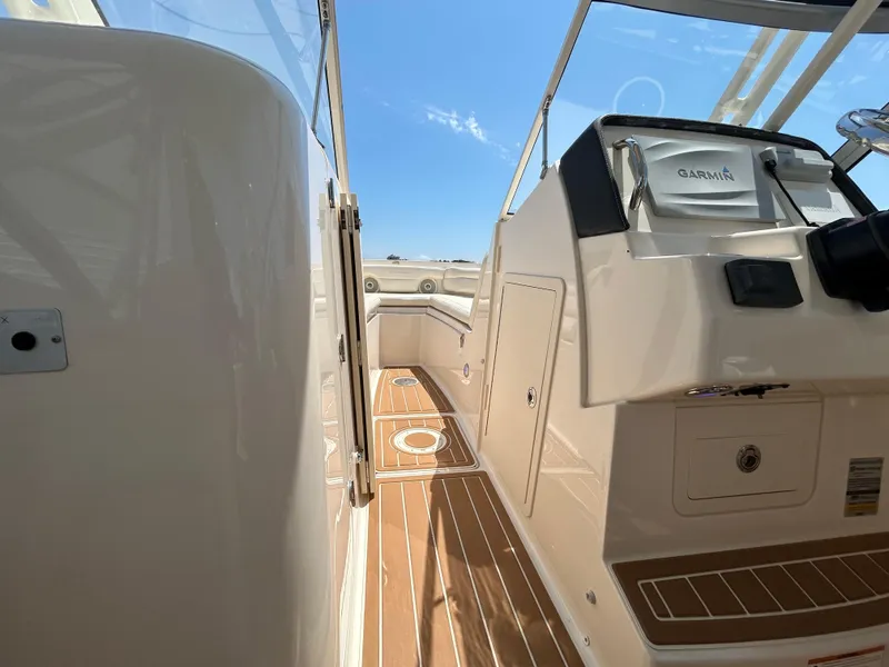 Slide: The Image of 2018 Grady-White Freedom 235 boat interior with Garmin navigation, wooden deck, and clear sky. - 27