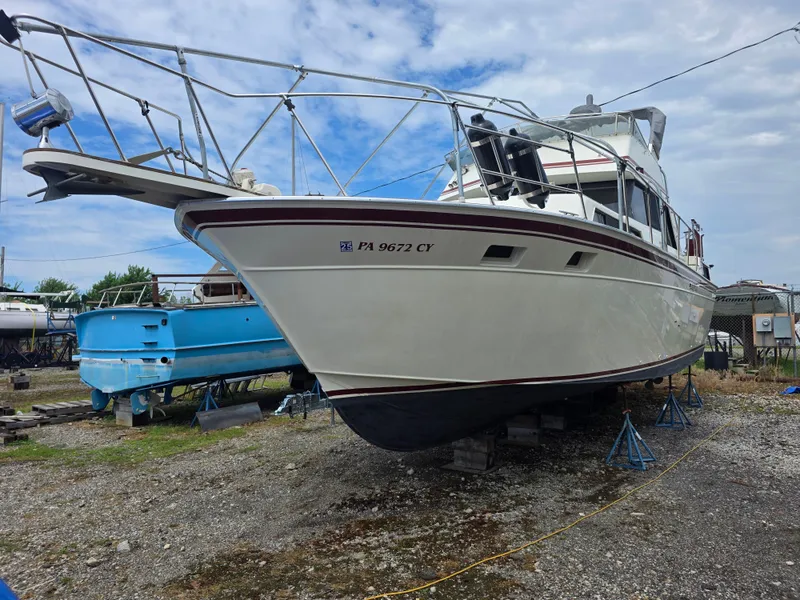The Image of 1988 Marinette 37 Motor Yacht on stands, ready for maintenance under a cloudy sky. - 1