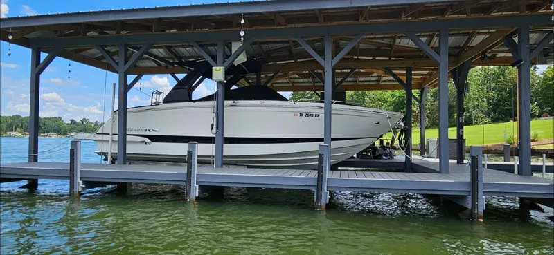 Slide: The Image of 2018 Chaparral 267 SSX boat docked under a wooden shelter on a lake. - 3
