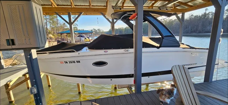 Slide: The Image of 2018 Chaparral 267 SSX boat docked under a covered structure by a lake. - 4