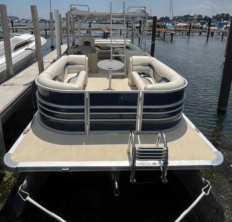 Slide: The Image of 2016 Custom King Mariner pontoon boat docked, featuring spacious seating and a swim ladder. - 2