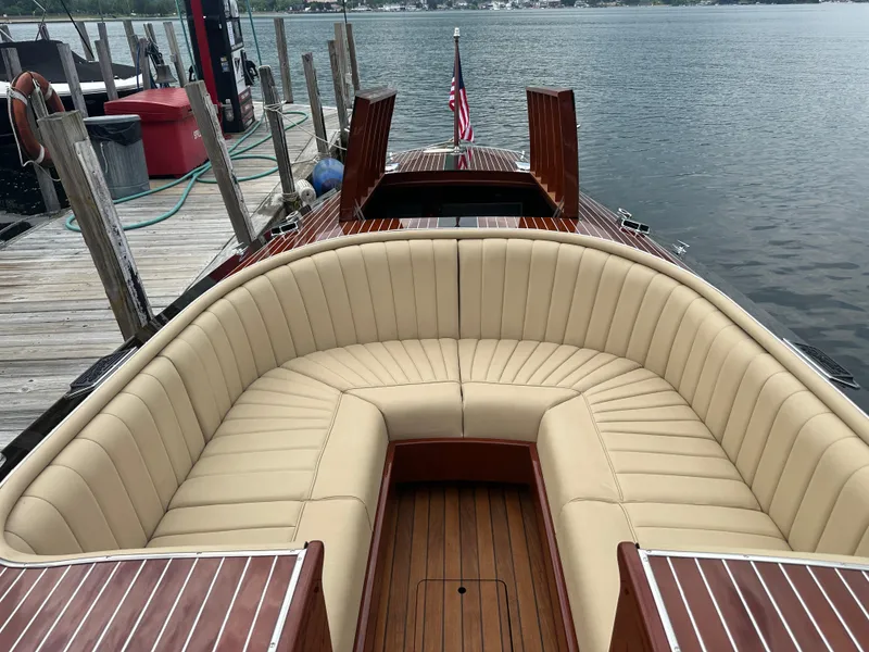 Slide: The Image of 1999 Hacker-Craft Custom Sport boat with beige seating, docked by a wooden pier. - 13