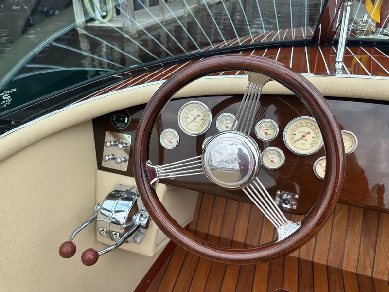 Slide: The Image of Steering wheel and dashboard of a 1999 Hacker-Craft Custom Sport boat with wood finish. - 14