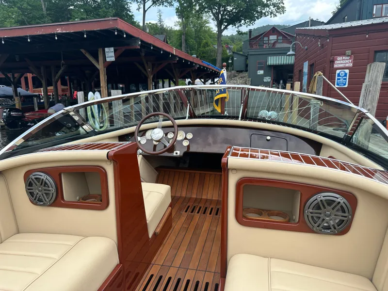 Slide: The Image of Interior of a 1999 Hacker-Craft Custom Sport boat with wooden accents and beige seating. - 16