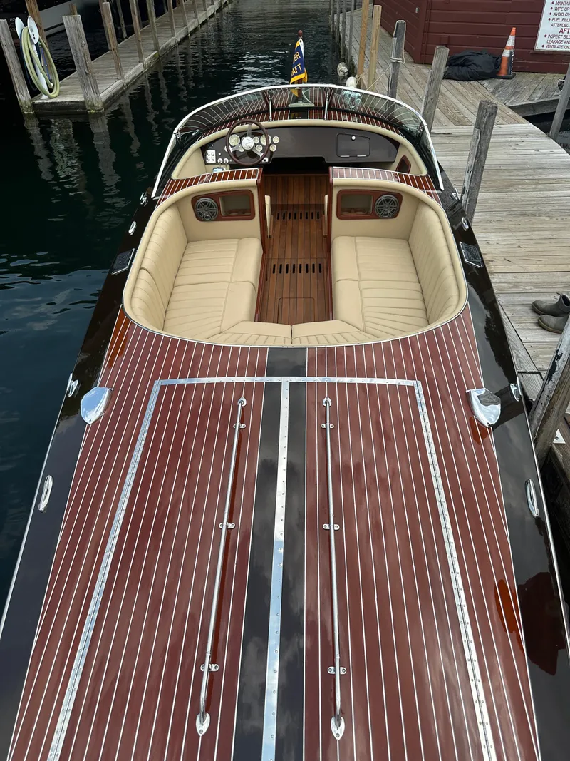 Slide: The Image of 1999 Hacker-Craft Custom Sport boat with polished wood finish and beige seating at a dock. - 17