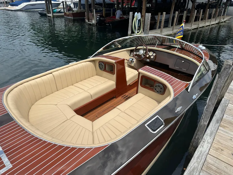 Slide: The Image of 1999 Hacker-Craft Custom Sport boat with elegant wood finish and beige seating at a dock. - 4