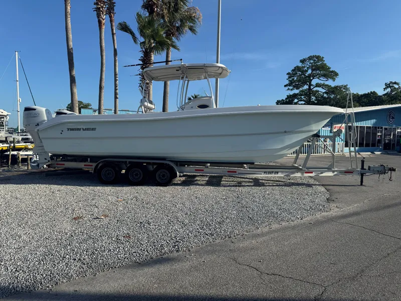 Slide: The Image of 2022 Twin Vee 310 CC GF Classic boat on trailer, parked near palm trees. - 0