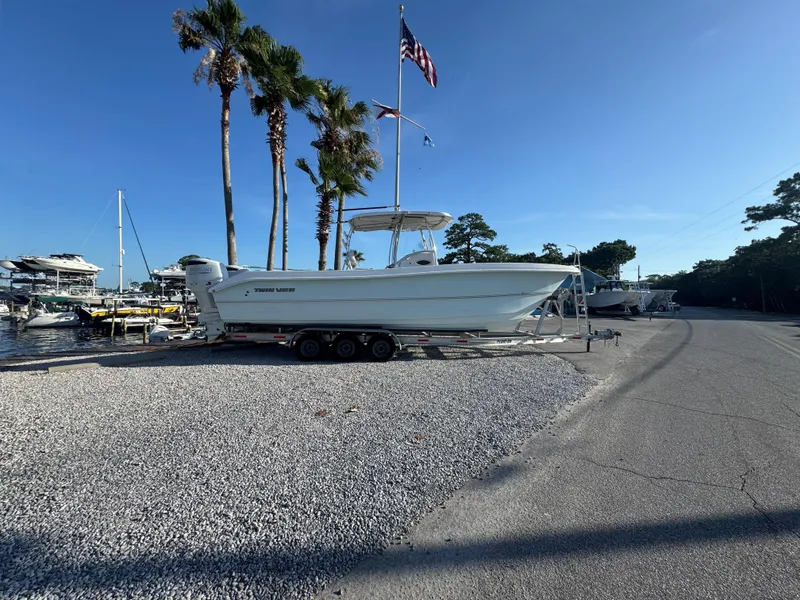 Slide: The Image of 2022 Twin Vee 310 CC GF Classic boat on trailer near palm trees and marina. - 1