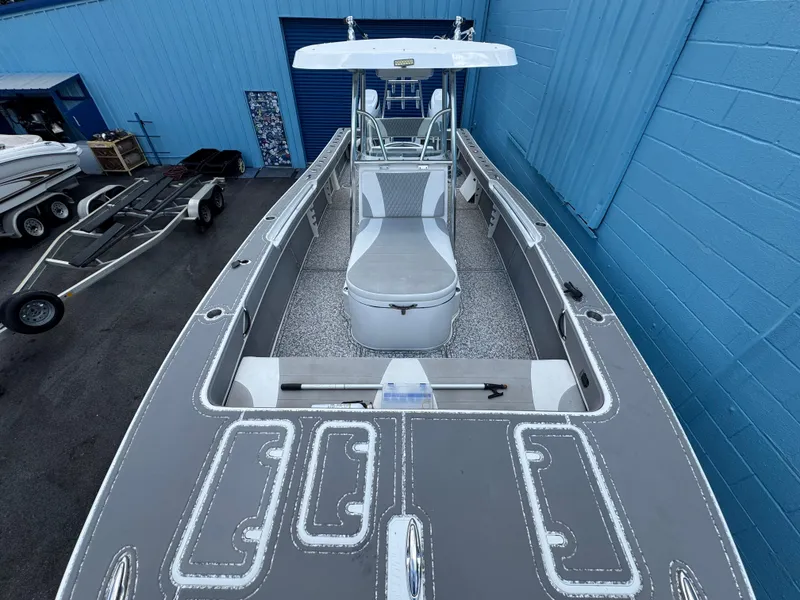 Slide: The Image of 2022 Twin Vee 310 CC GF Classic boat, gray deck, white seating, parked near blue building. - 4