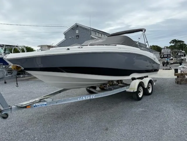 Slide: The Image of 2023 NauticStar 223 DC boat on trailer, parked outdoors, under cloudy sky. - 3