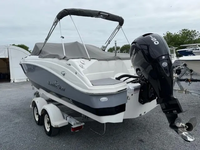 Slide: The Image of 2023 NauticStar 223 DC boat on trailer with outboard motor, parked outdoors. - 5