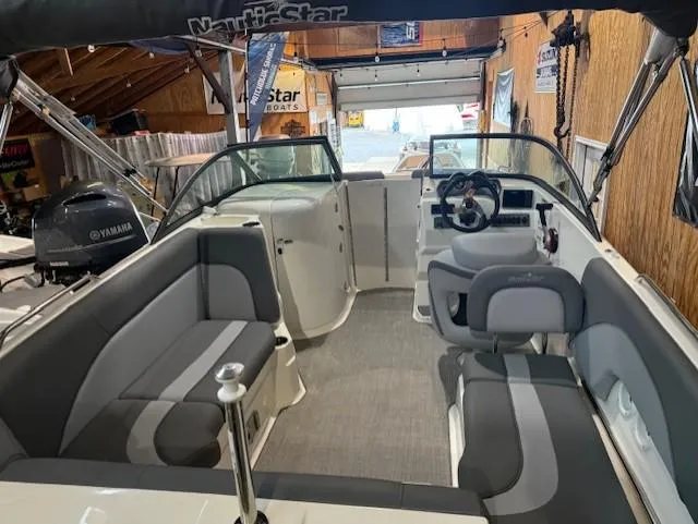 Slide: The Image of 2023 NauticStar 223 DC boat interior with gray seating and Yamaha engine in a garage. - 6