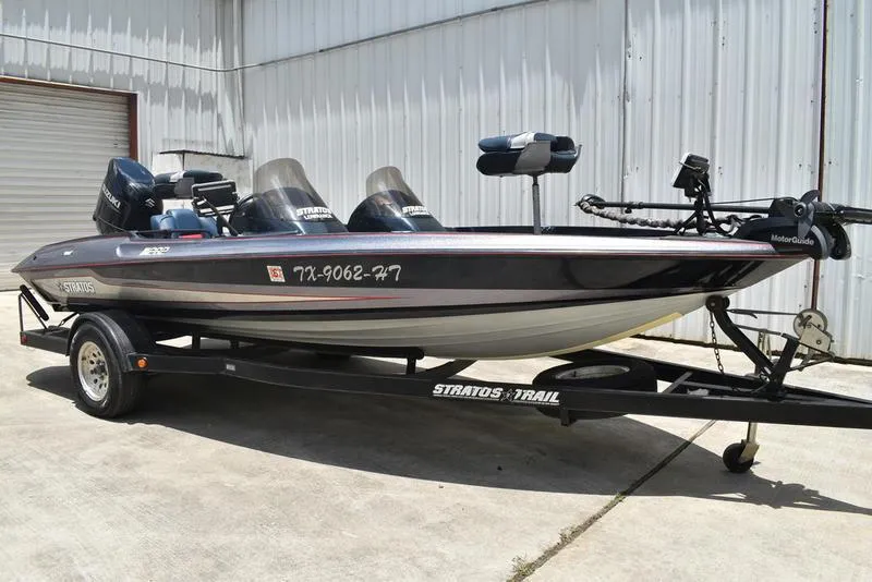 Slide: The Image of 1997 Stratos 282 DC boat on trailer, parked near a metal building. - 6