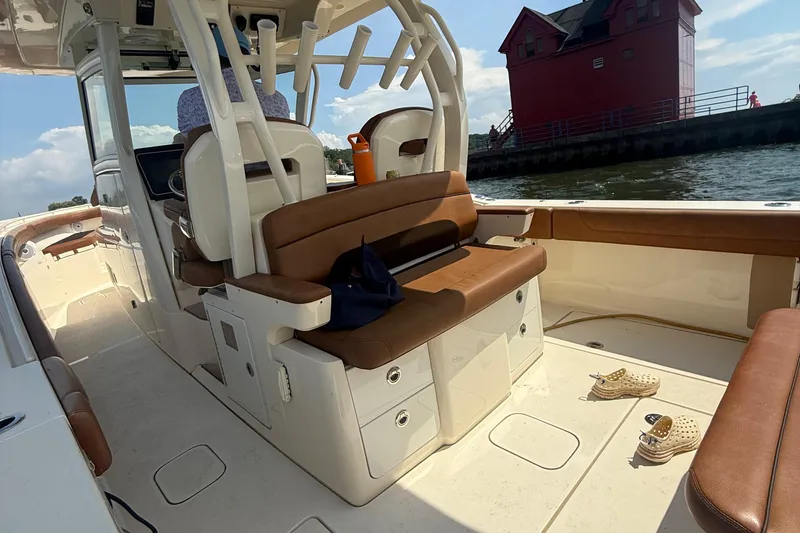 Slide: The Image of 2016 Scout 350 LXF boat interior with brown seating, docked near a red building. - 16