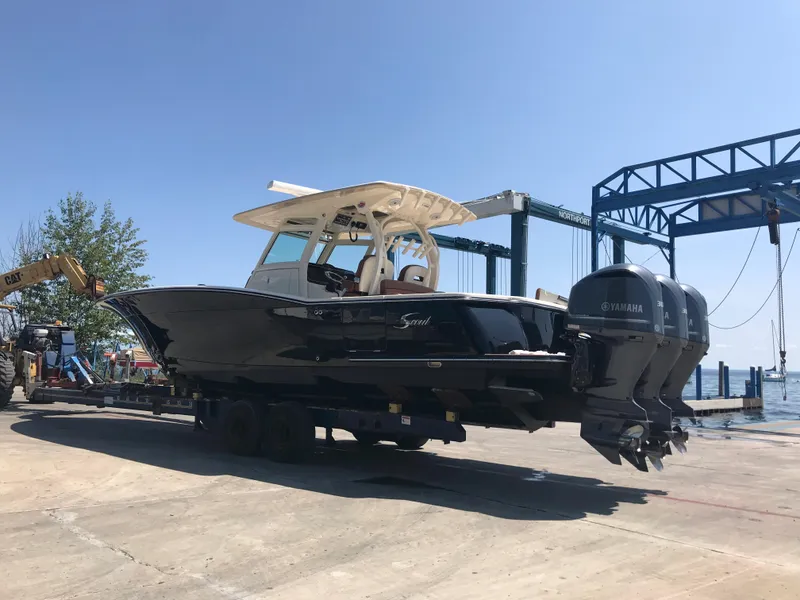Slide: The Image of 2016 Scout 350 LXF boat with dual Yamaha engines on a trailer by the water. - 2