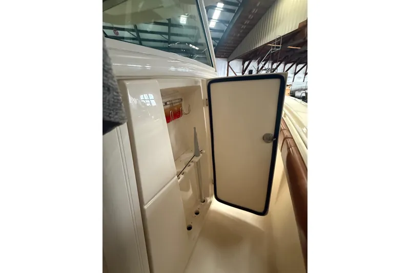 Slide: The Image of 2016 Scout 350 LXF boat storage compartment with open door in a marina setting. - 26