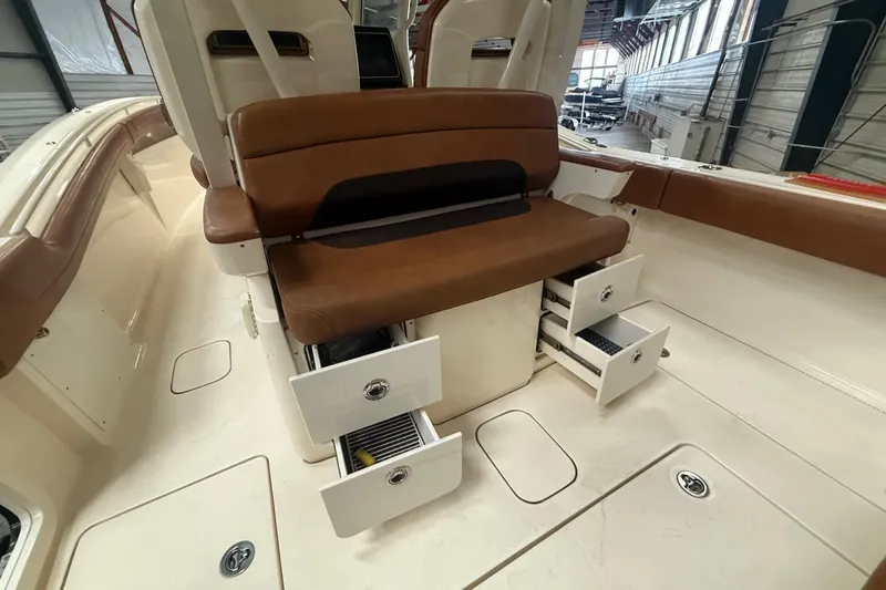Slide: The Image of 2016 Scout 350 LXF boat interior with brown seating and open storage drawers. - 29