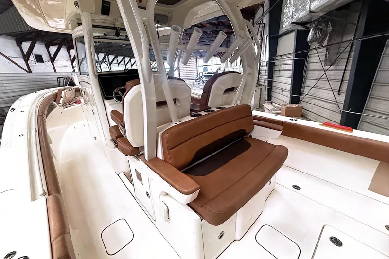 Slide: The Image of 2016 Scout 350 LXF boat interior with brown seating and white deck in a warehouse. - 30