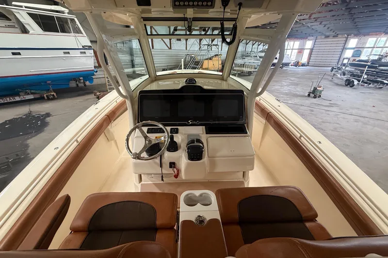 Slide: The Image of 2016 Scout 350 LXF boat interior with helm, steering wheel, and seating in a storage facility. - 31