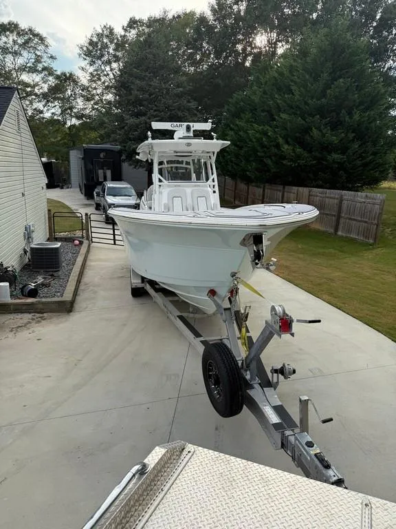 Slide: The Image of 2022 Sea Fox 328 Commander boat on trailer in driveway, surrounded by trees and houses. - 4