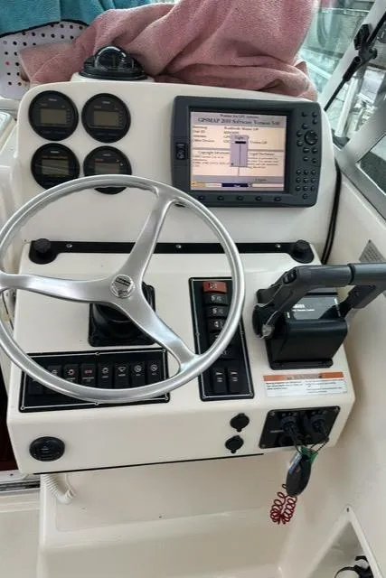 Slide: The Image of 2003 Pursuit 3070 Express boat dashboard with steering wheel, gauges, and navigation system. - 14