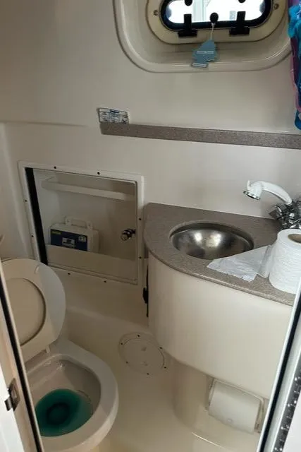 Slide: The Image of Compact bathroom in a 2003 Pursuit 3070 Express boat, featuring a toilet and sink. - 16
