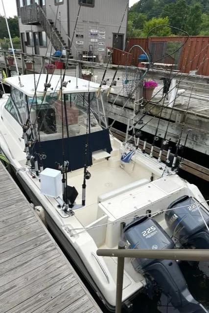 Slide: The Image of 2003 Pursuit 3070 Express boat docked, equipped with fishing rods and twin 225 horsepower engines. - 2