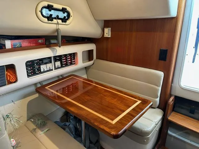 Slide: The Image of 2003 Pursuit 3070 Express cabin with wood table and beige seating. - 4