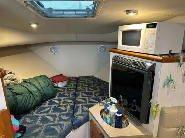 Slide: The Image of 2003 Pursuit 3070 Express cabin with bed, microwave, and compact kitchen area. - 7