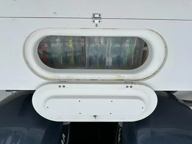 Slide: The Image of 2003 Pursuit 3070 Express boat storage compartment with visible fishing gear inside. - 8