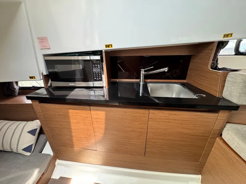 Slide: The Image of 2022 Beneteau Flyer 9 SUNdeck interior kitchen with microwave, sink, and wooden cabinetry. - 21