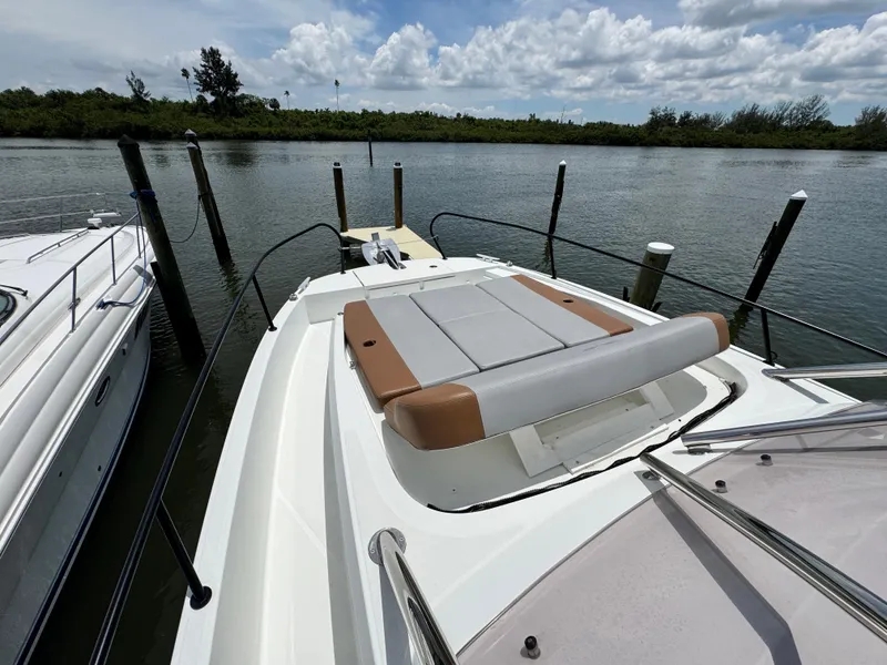 Slide: The Image of 2022 Beneteau Flyer 9 SUNdeck moored by a serene waterfront, showcasing its spacious deck. - 26