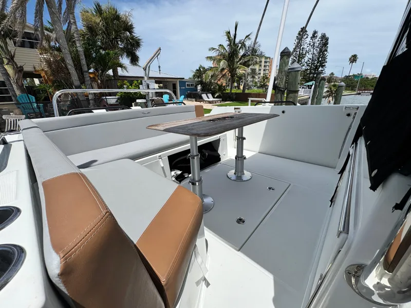 Slide: The Image of 2022 Beneteau Flyer 9 SUNdeck boat interior with seating and table, docked near palm trees. - 6