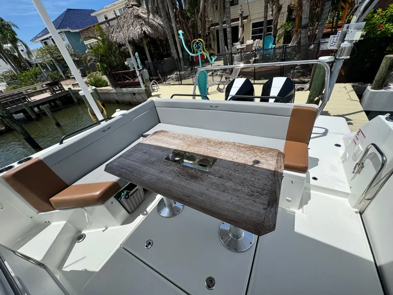 Slide: The Image of 2022 Beneteau Flyer 9 SUNdeck boat interior with seating and table, docked near waterfront homes. - 8