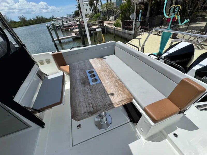 Slide: The Image of 2022 Beneteau Flyer 9 SUNdeck boat with spacious seating and wooden table, docked by the water. - 9
