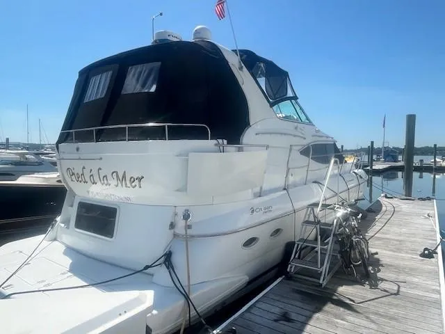 Slide: The Image of 2000 Cruisers Yachts 4450 Express Motoryacht docked at marina under clear blue sky. - 3