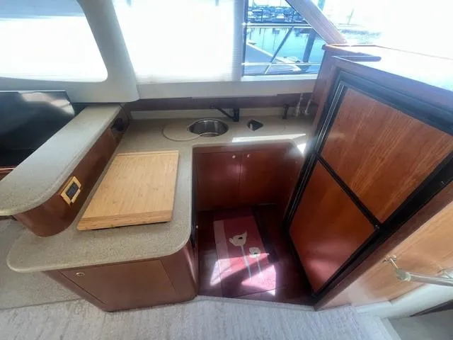 Slide: The Image of 2000 Cruisers Yachts 4450 Express Motoryacht kitchen with sink, countertop, and wooden cabinetry. - 34